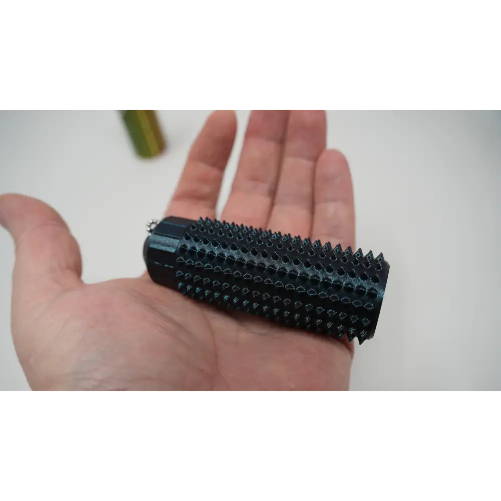 black 3D printed Ouchie fidget keychain stress reliever with spikes held in hand