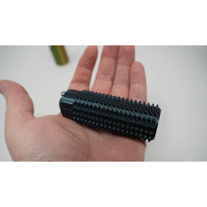 black 3D printed Ouchie fidget keychain stress reliever with spikes held in hand